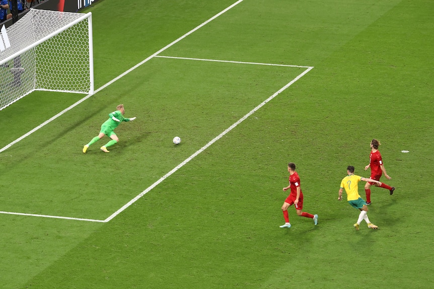 Kasper Schmeichel dives towards a ball as Mat Leckie completes his shot