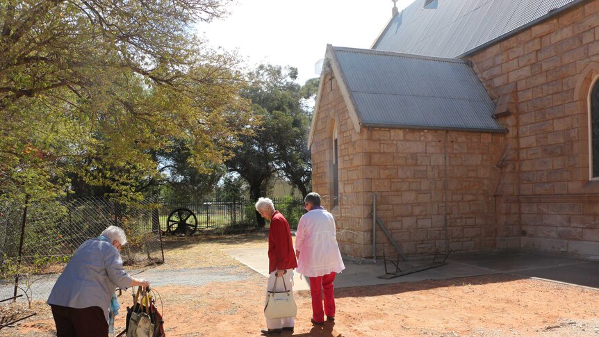 Three members of the tiny congregation walk towards the St James's Anglican Church at Wilcannia.