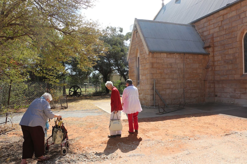 Three members of the tiny congregation walk towards the St James's Anglican Church at Wilcannia.
