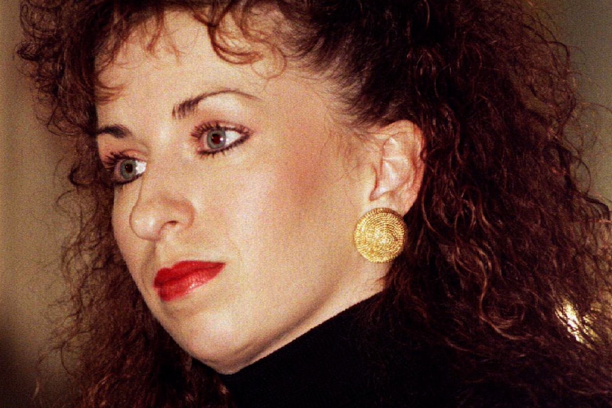 Paula Jones, wearing a black turtleneck top, stares ahead.