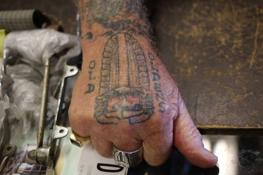 An old Holden logo tattoo on an older man's hand