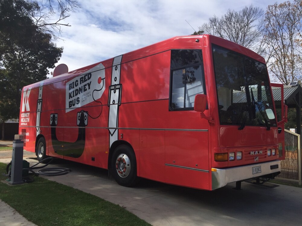 Big Red Kidney Bus parked at a Mildura caravan park