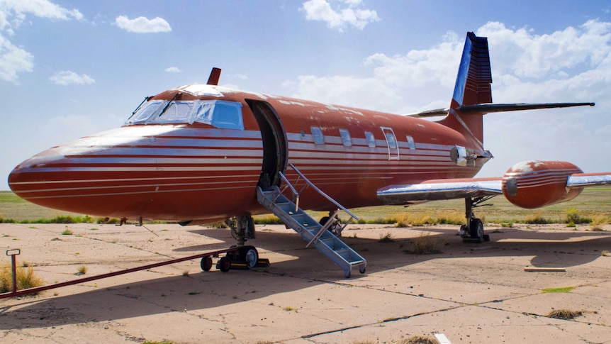 A red and silver private jet, once owned by Elvis Presley, on a runway in New Mexico.