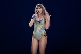 Taylor Swift sings into a microphone on stage in Sydney while dressed in a sequin bodysuit.