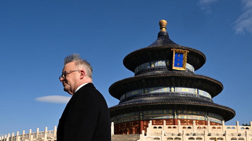 Albanese's hair sticks up in the wind as he walks past a Chinese temple