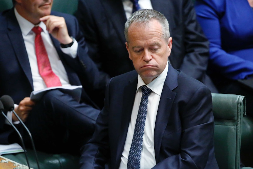 Opposition Leader Bill Shorten sighs during Question Time. He's wearing a navy suit and dark blue tie