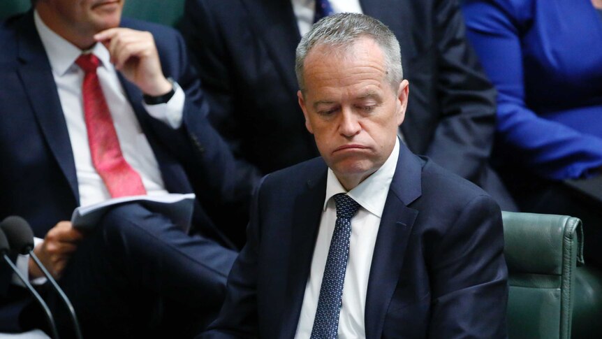 Opposition Leader Bill Shorten sighs during Question Time. He's wearing a navy suit and dark blue tie