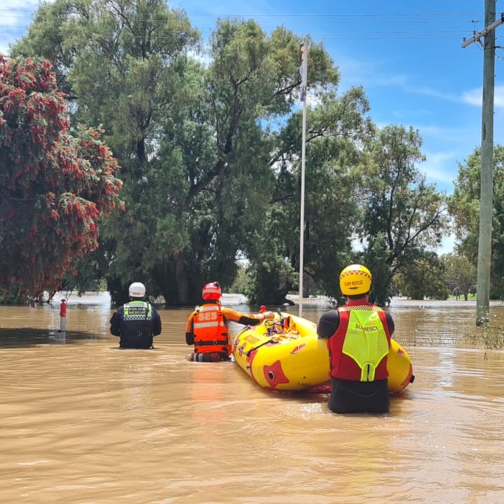 ses volunteers push a boat through floodwater