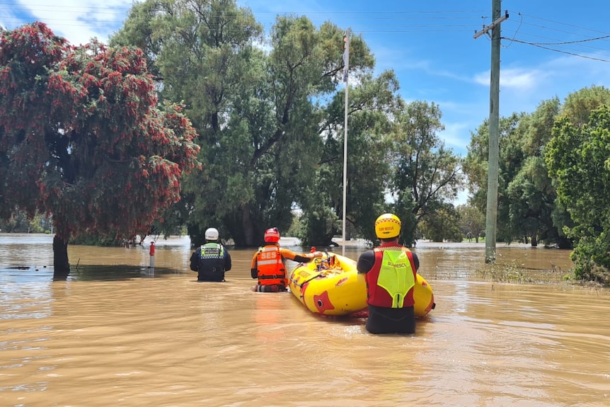 ses volunteers push a boat through floodwater