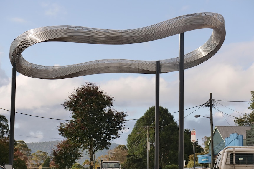 Swirling ring sculpture made of aluminium coils hoisted in the main street of a country town