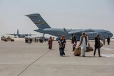People walk on a tarmac in front of a airplane in Kabul