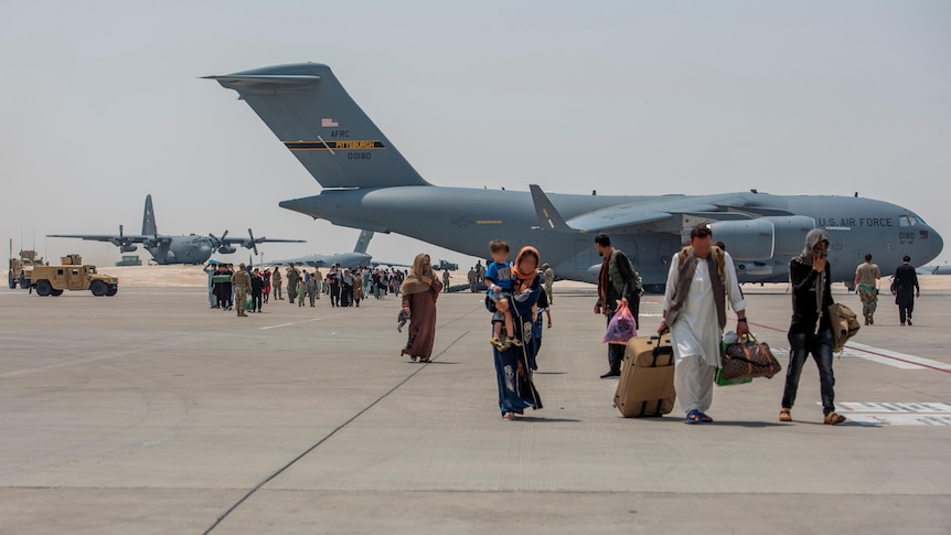 People walk on a tarmac in front of a airplane in Kabul