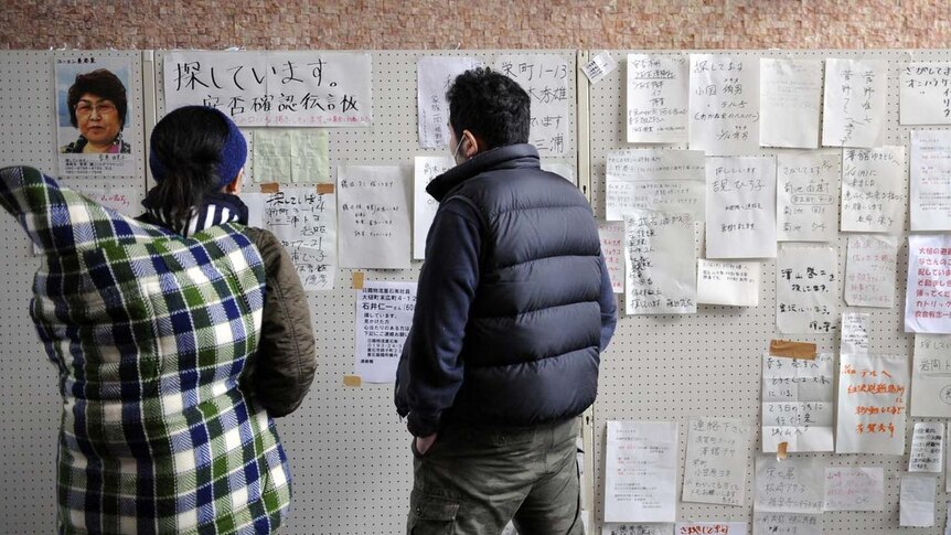 Survivors check a message board in the earthquake and tsunami-ravaged town of Otsuchi.