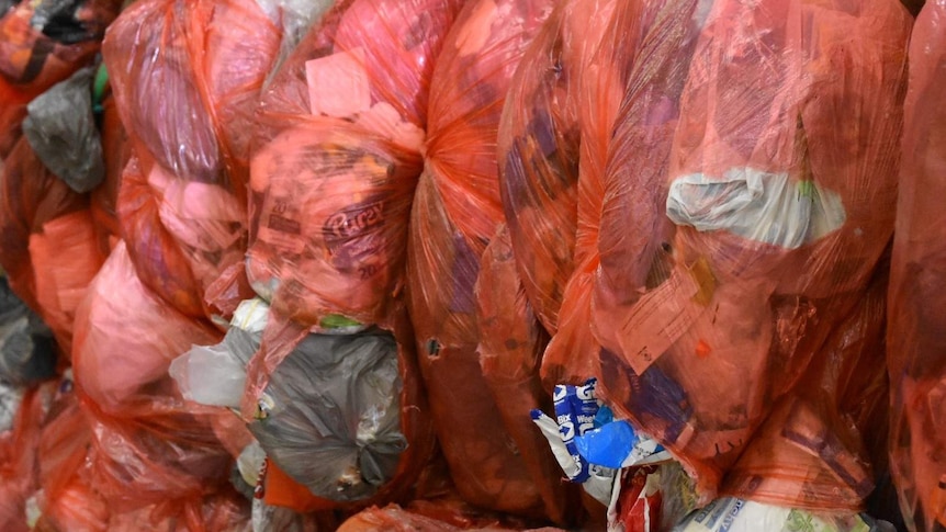 A large pile of plastic shopping bags filled with other recylables.