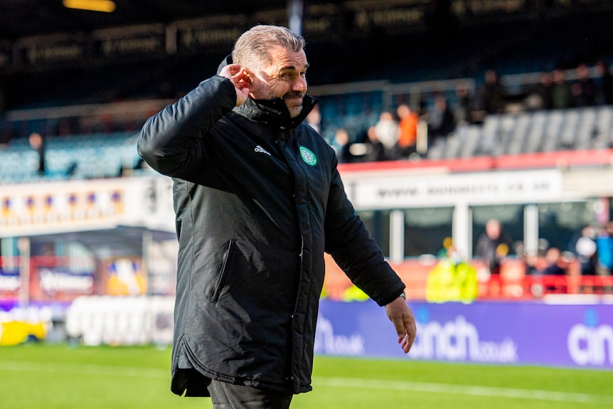 Ange Postecoglou cups his hand to his ear and grimaces