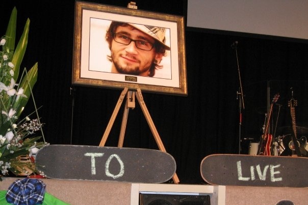 A memorial service for Jeremy Earnshaw with his photo in a frame on stage.