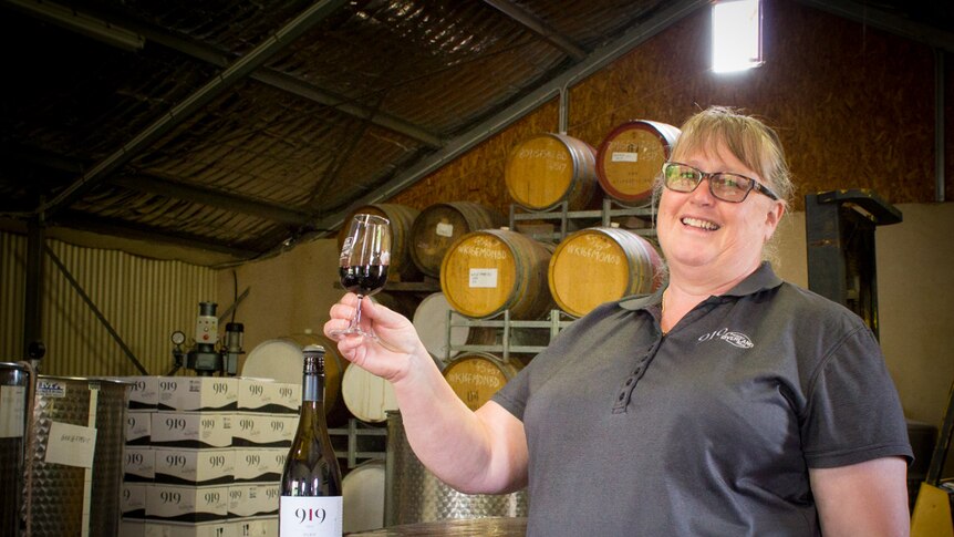 Jenny Semmler holds up a glass or red wine.