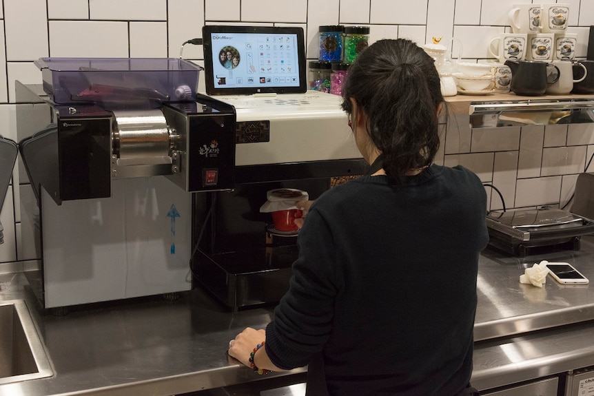 A staff member at ChanGe cafe uses the coffee printer machine