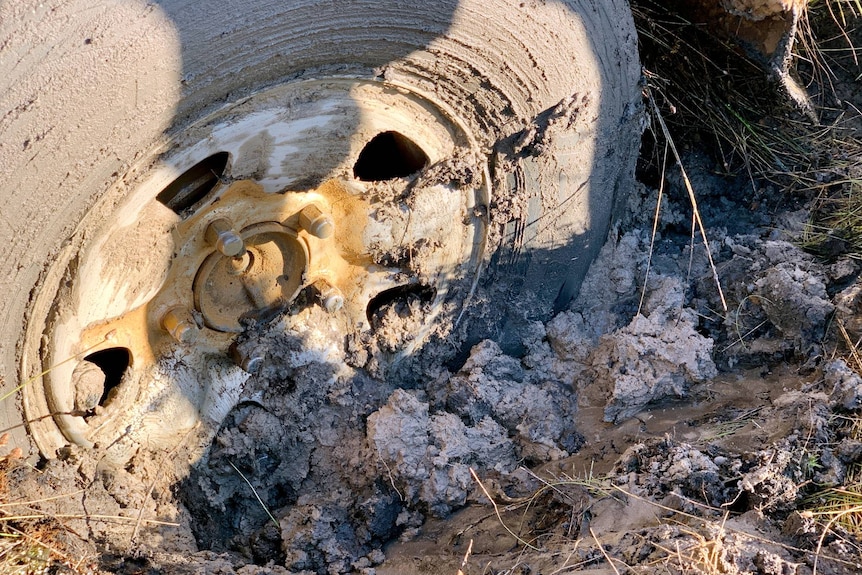 Close-up of a wheel bogged in dirt.
