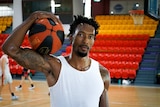 RJ Jarrett holds a basketball above his shoulder at basketball training.