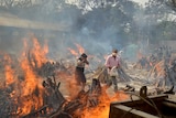 People walk among flaming funeral pyres