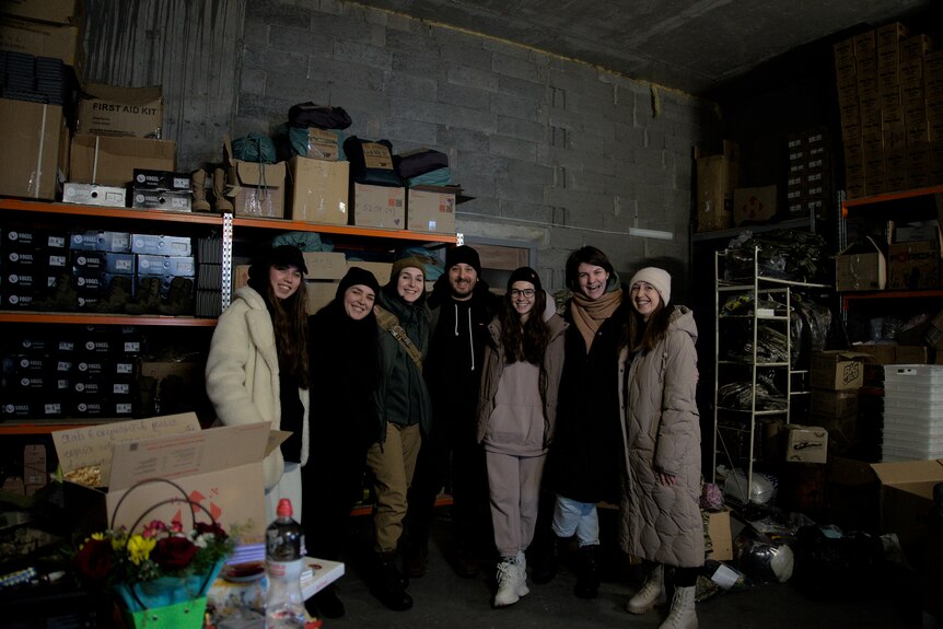 A group photo of volunteers in a warehouse with boots and military uniforms. 