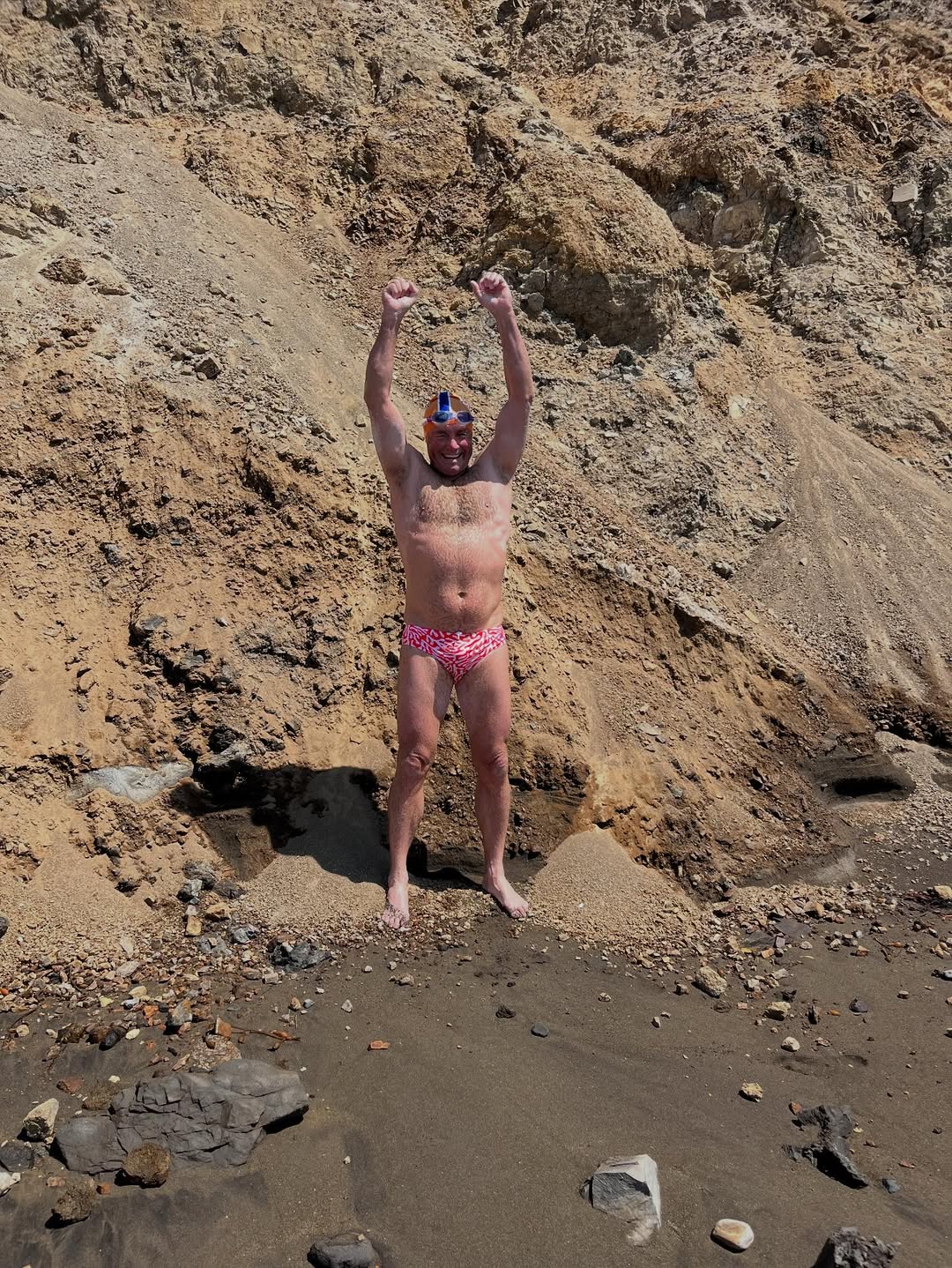 A man with his hands in the air after completing the Catalina Channel swim.
