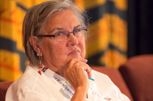 An Indigenous woman sits thinking, with her hand on her chin.