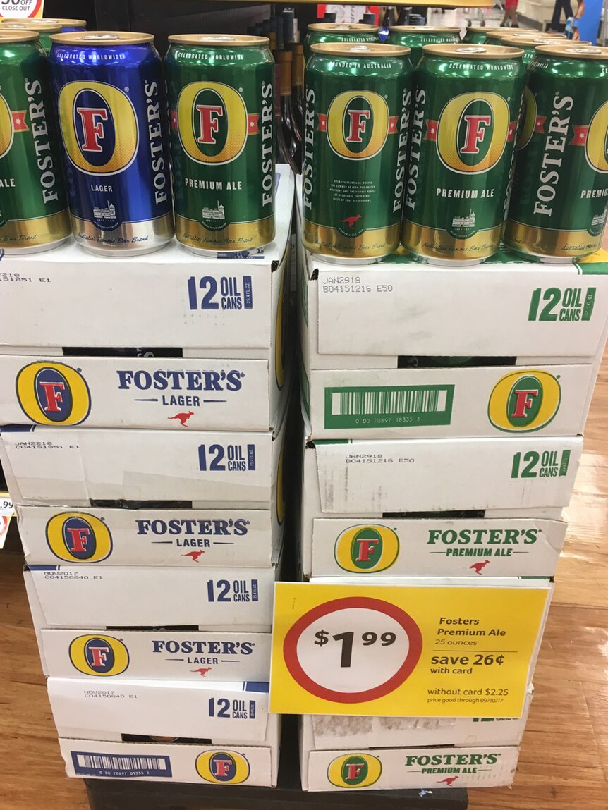 Cartons of Fosters lager and premium ale piled in a supermarket with special sign discounting them to $1.99 a can.