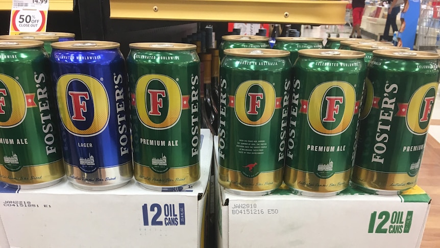 Cartons of Fosters lager and premium ale piled in a supermarket with special sign discounting them to $1.99 a can.