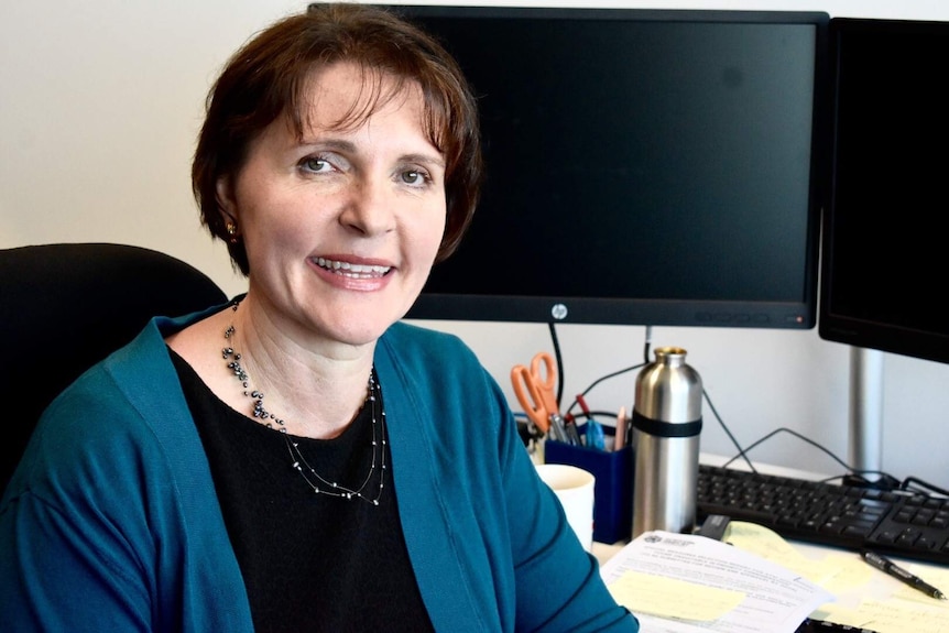 NT Public Guardian Beth Walker sitting at her desk smiling at the camera.