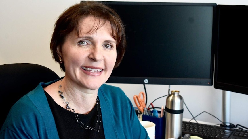 NT Public Guardian Beth Walker sitting at her desk smiling at the camera.