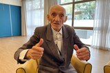 Elderly man with both of his thumbs up. 