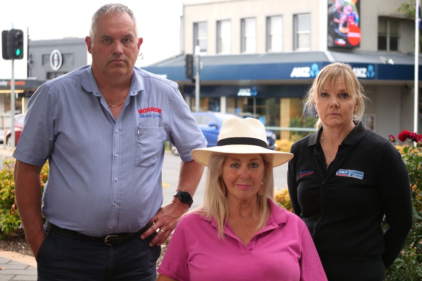 one man and two women stand on a street corner in the main street of Horsham
