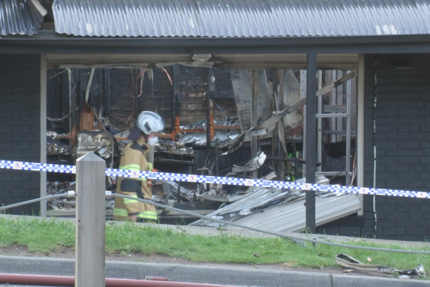 A firefighter walks past a store gutted by fire.