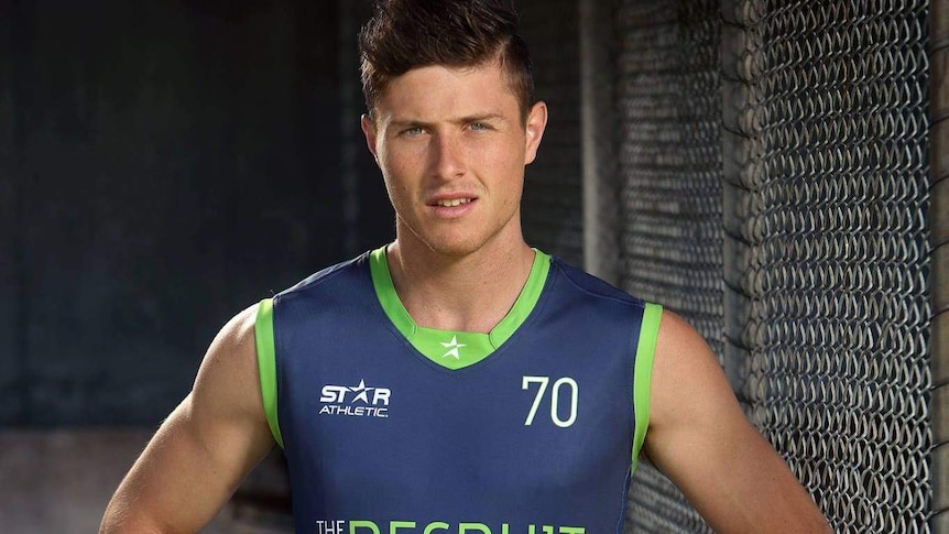 A man stands with his arms on his hips in a football guernsey