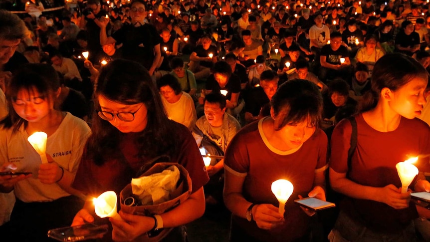 A night time gathering of people holding candles in Hong Kong.