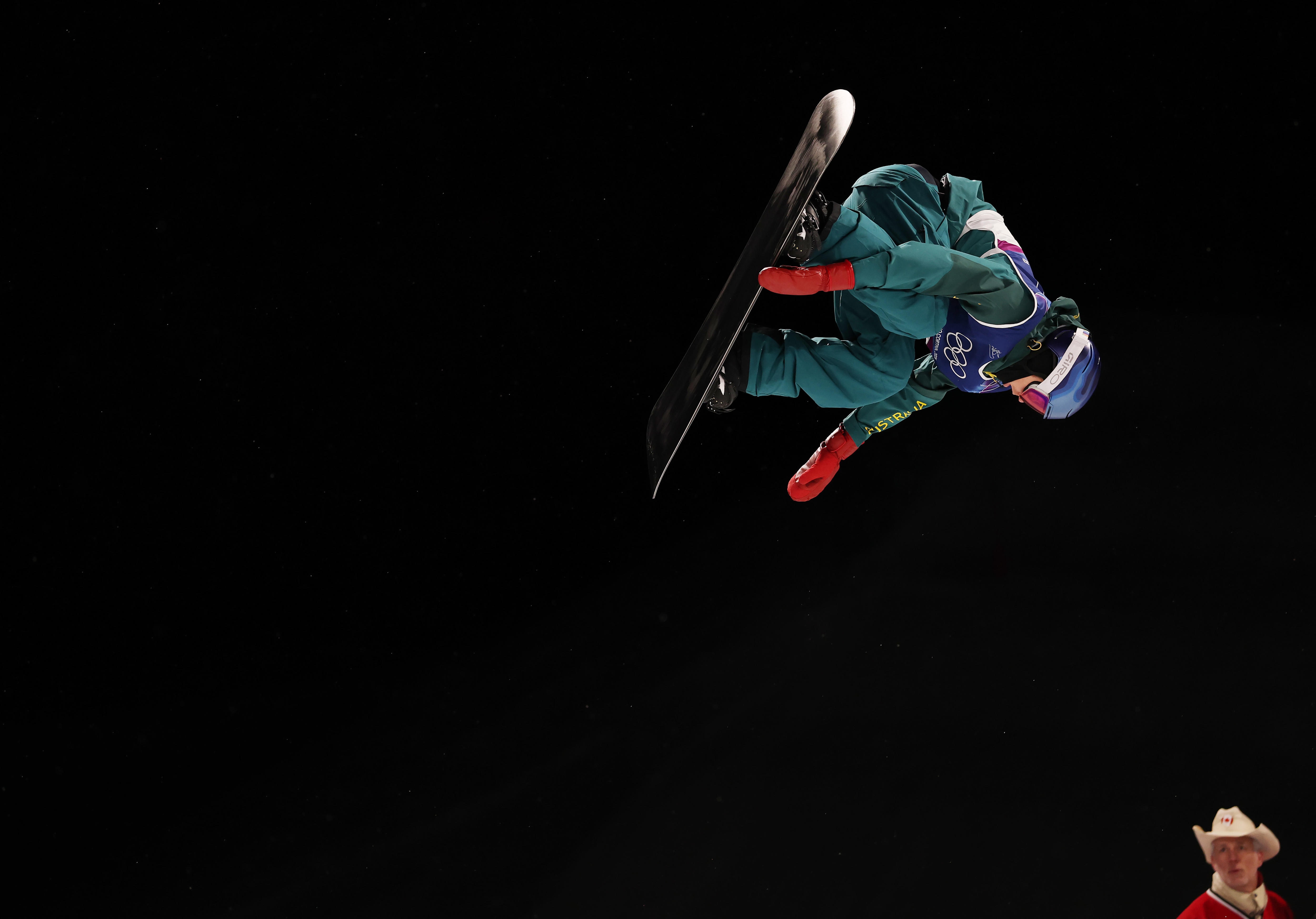 Un snowboarder agarra su tabla mientras vuela por el aire.