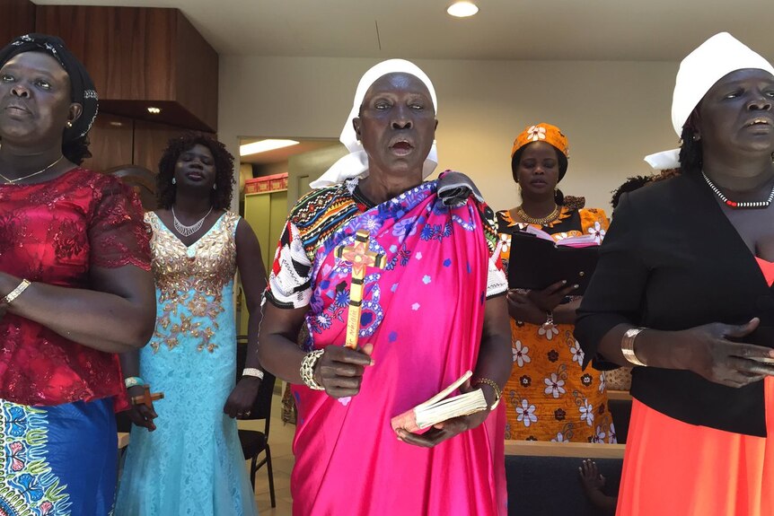 Sudanese migrant women wearing colourful dresses sing for a Christmas service in Melbourne.