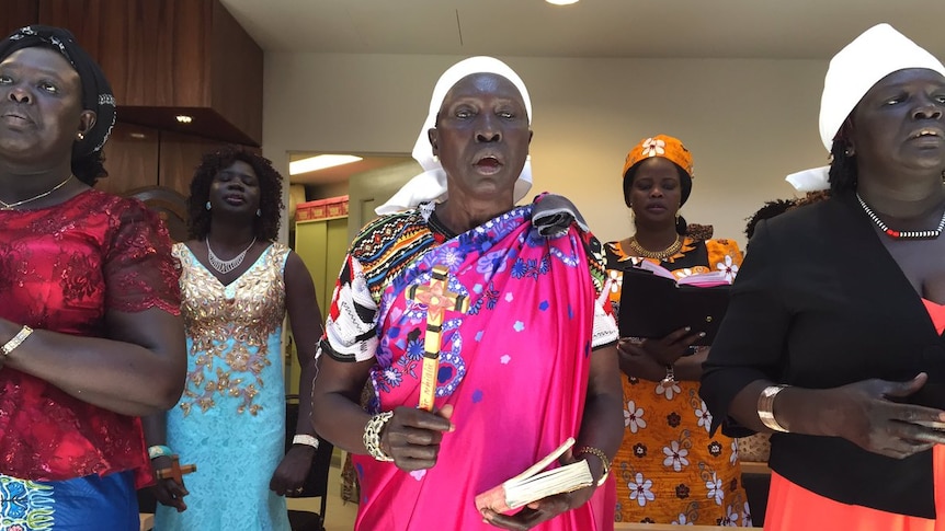 Sudanese migrant women wearing colourful dresses sing for a Christmas service in Melbourne.