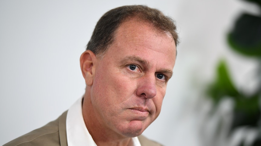 Alen Stajcic looks towards the camera wearing a beige suit jacket and white shirt