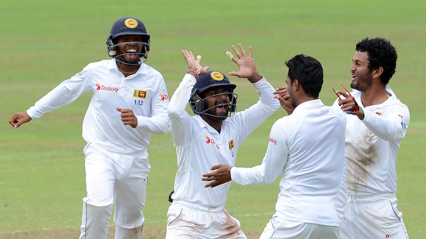 Sri Lanka's cricket team celebrating on day five of test, four people are cheering, smiling, and high-fiving each other.