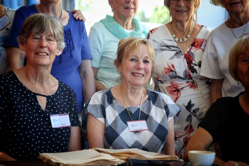 An older woman poses for a photo in a group.