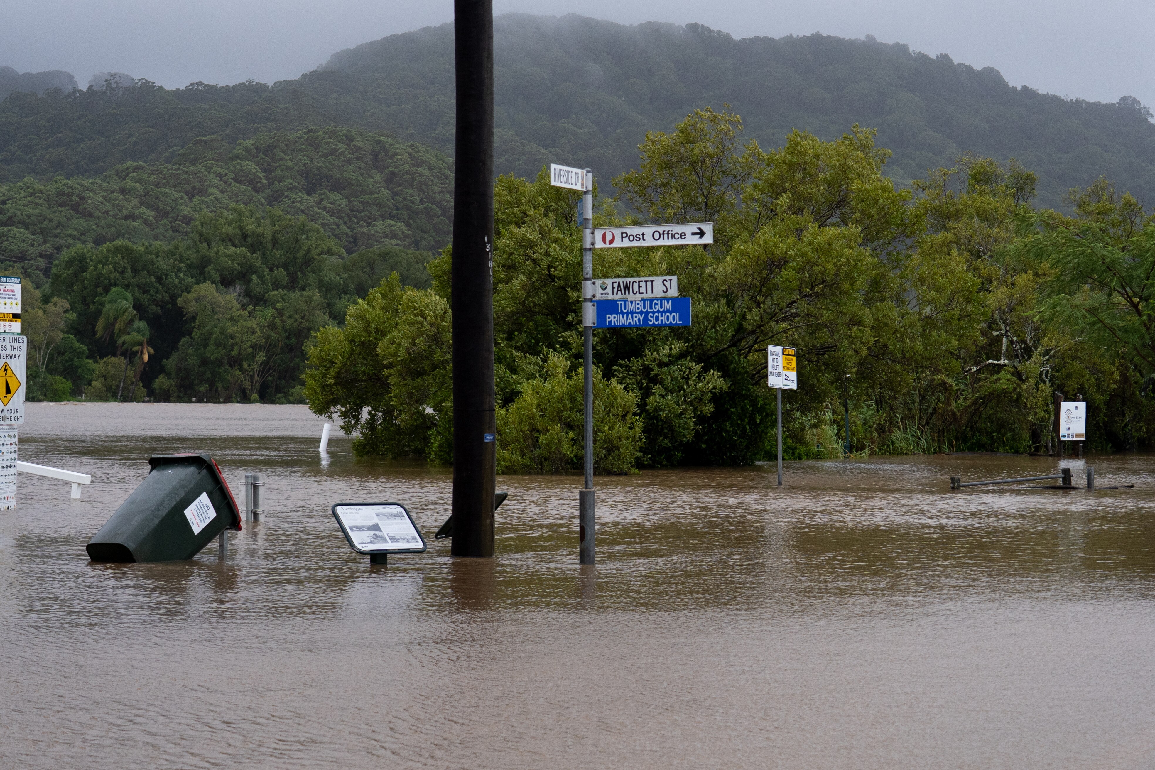 A street covered by flood waters, with street signs poking above the water