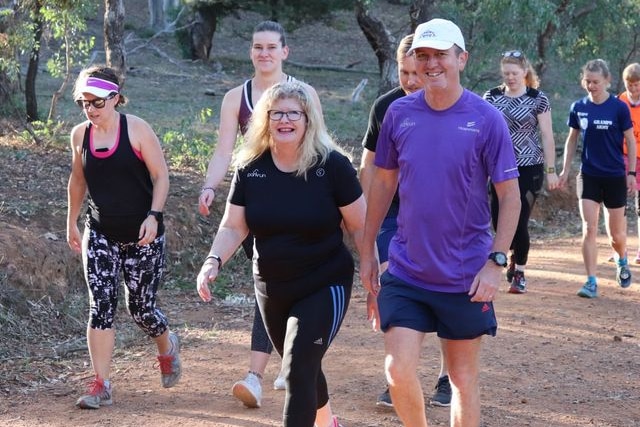 Suzanne Crane walks on a dirt track beside a man and in front of two women.