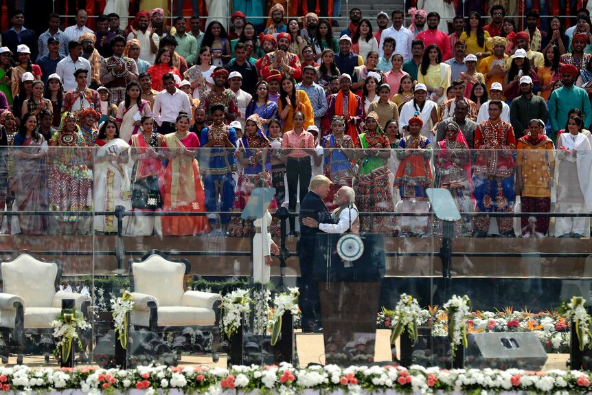 Donald Trump hug Narendra Modi in front of a crowd.