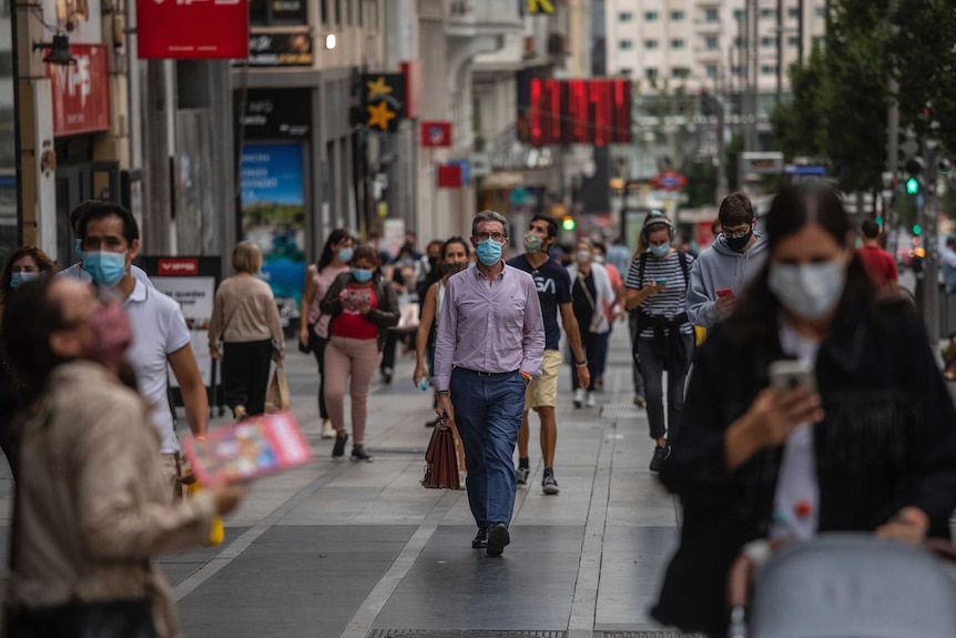 People walk on a street in masks in Madrid.