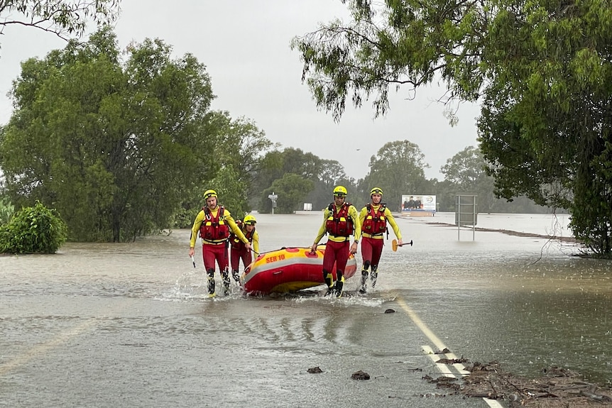 Rescue crews exit flood waters carrying a boat.
