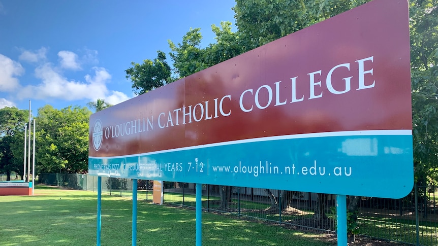 A large sign saying "O'Loughlin Catholic College" on a patch of grass.