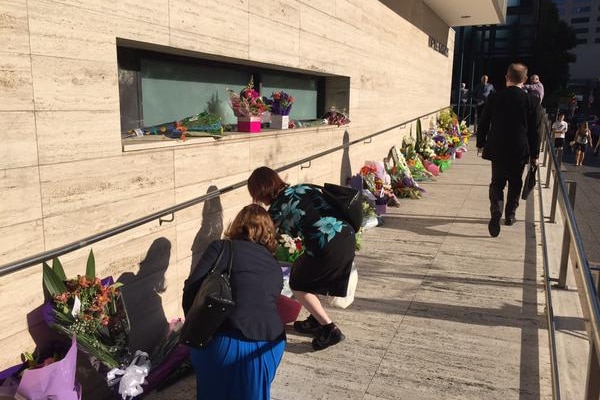 Floral tributes are laid at the entrance of Parramatta Police headquarters